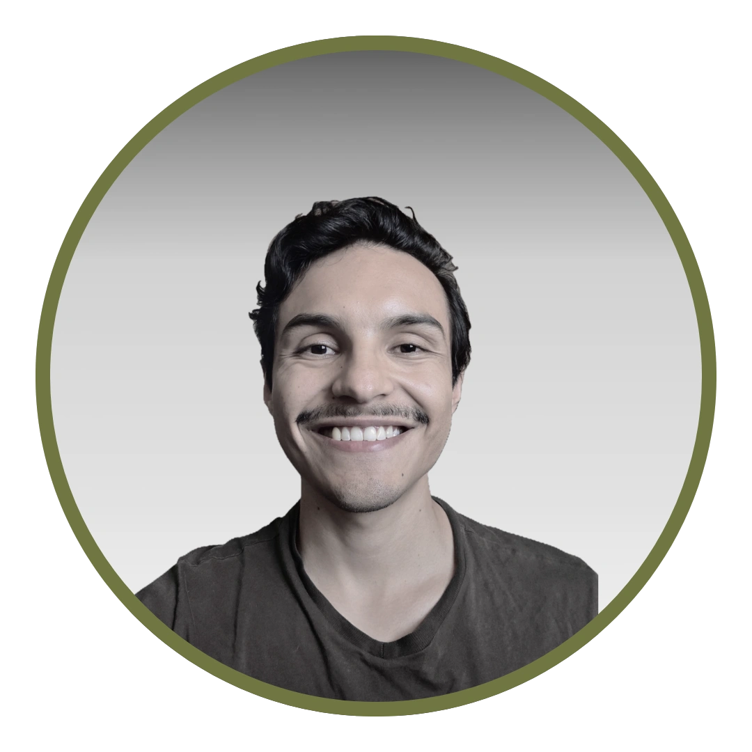 Retrato de David Vega en blanco y negro, recortado en un círculo con anillo verde oliva: mira a la cámara y sonríe, con el pelo oscuro y rizado, bigote y una camiseta oscura de cuello en pico.