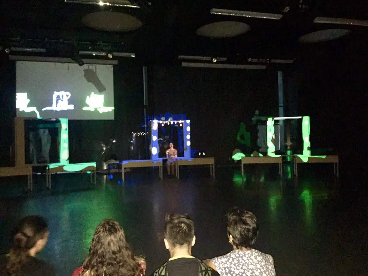 Vista d'insieme della messa in scena, con schermi e un tavolo su cui è proiettato il video mapping durante lo spettacolo