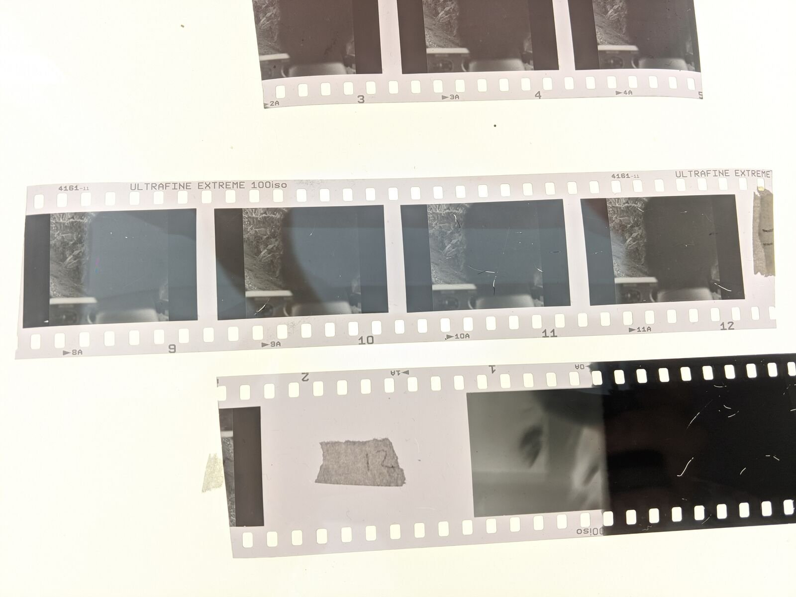 Tiras de película de 35 mm reveladas sobre un fondo blanco, con los cuadros de las fotografías refotografiadas.