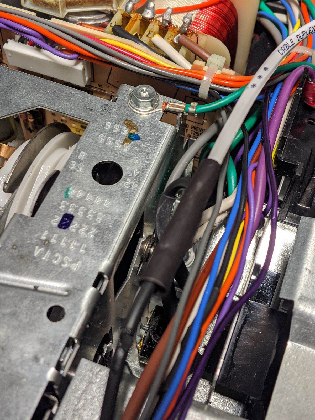 Interior abierto de un proyector de diapositivas: cables de colores, una bobina de cobre y el chasis metálico del mecanismo.