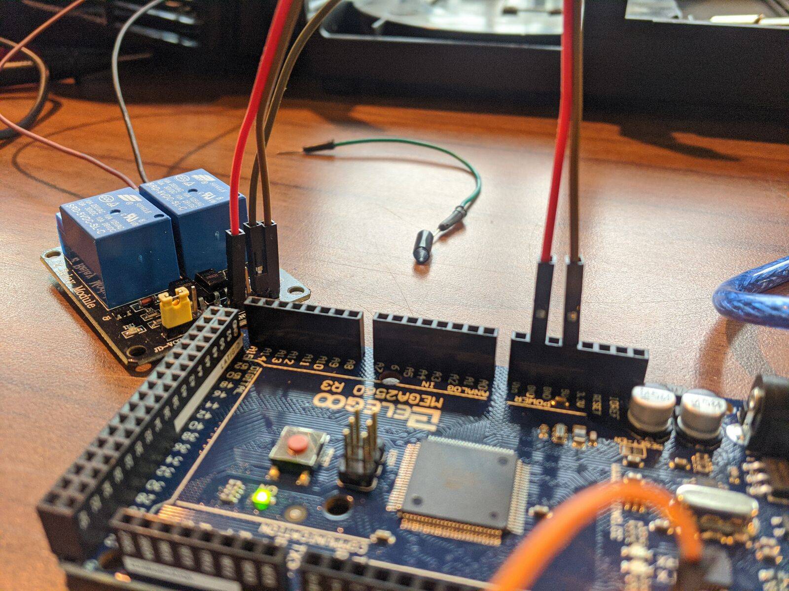 Módulo de dos relés azules conectado con cables de puente a una placa Arduino Mega.
